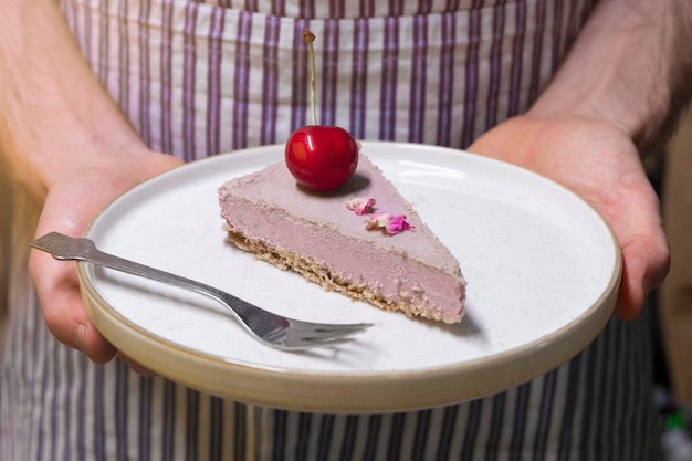 Panettiere che tiene un piatto con una fetta di deliziosa torta cruda del deserto sano