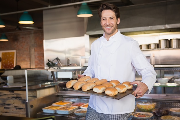 Panettiere felice che mostra vassoio con pane