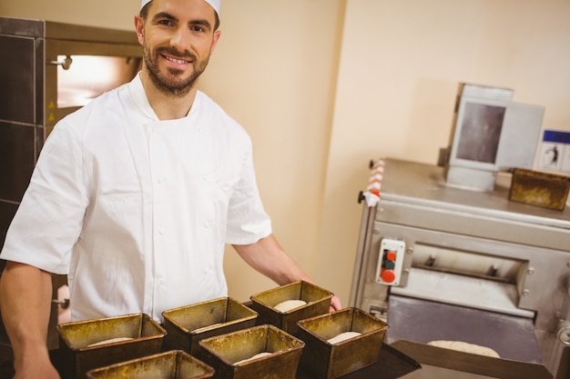 Panettiere felice che tiene vassoio di latte di pagnotta