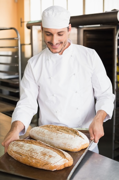 Panettiere felice che tiene vassoio di pane fresco