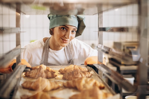 Panettiere femminile in cucina che tiene croissant appena sfornati