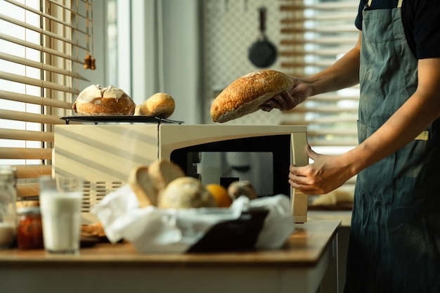 Panettiere maschio che prende il pane appena sfornato dal forno Mangiare sano concetto tradizionale di panetteria e pasticceria