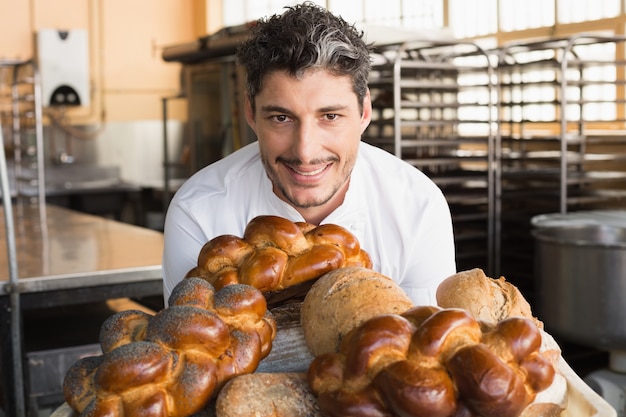 Panettiere sorridente che mostra bordo di pani