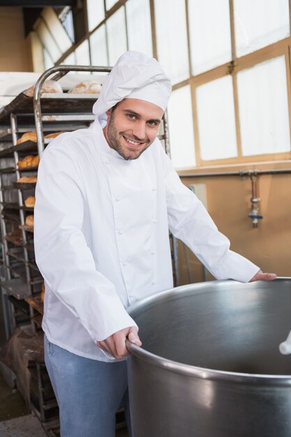 Panettiere sorridente che si appoggia miscelatore industriale