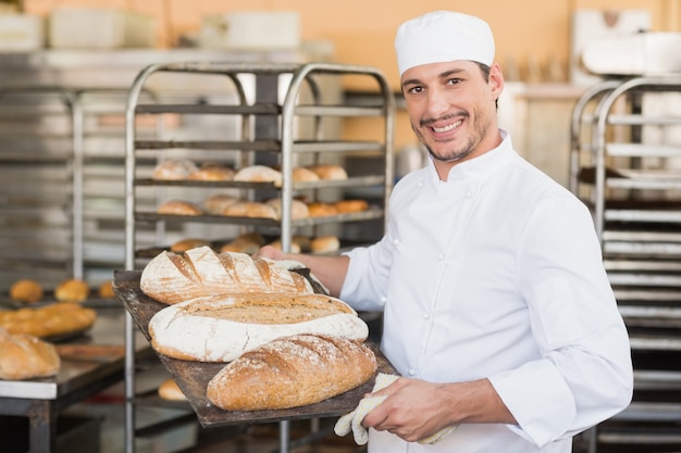 Panettiere sorridente che tiene vassoio di pane