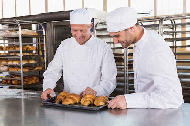 Panettieri sorridenti che guardano i vassoi dei croissant