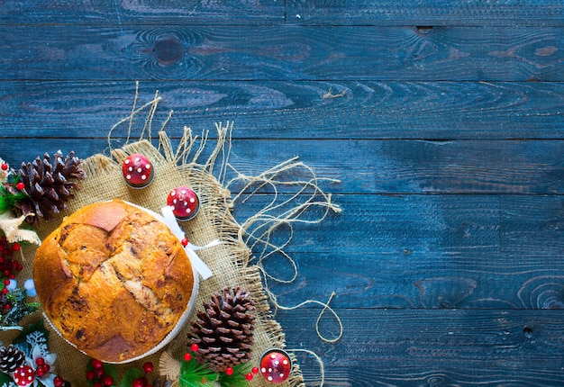 Panettone al cioccolato italiano Torta natalizia con palline decorazioni coni di Natale su uno sfondo di legno.