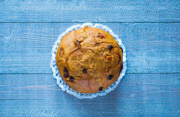 Panettone con frutta e decorazioni natalizie su fondo in legno