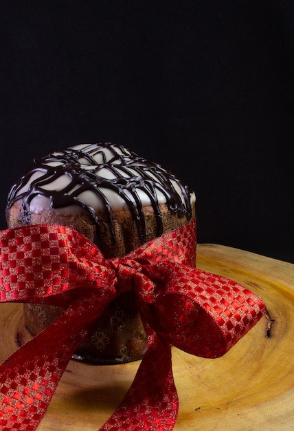 Panettone sopra una scrivania di legno con una cravatta rossa su sfondo nero