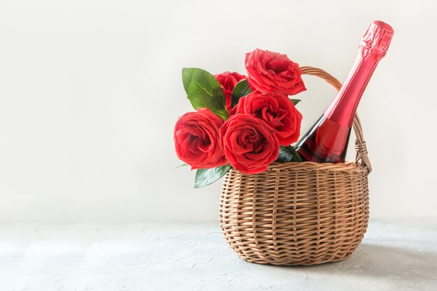 Paniere regalo, bouquet di rose rosse, bottiglia di champagne su bianco. Carta di San Valentino. Regalo romantico.