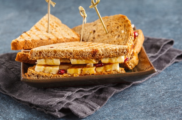 Panini al burro di arachidi con banana sul piatto scuro.