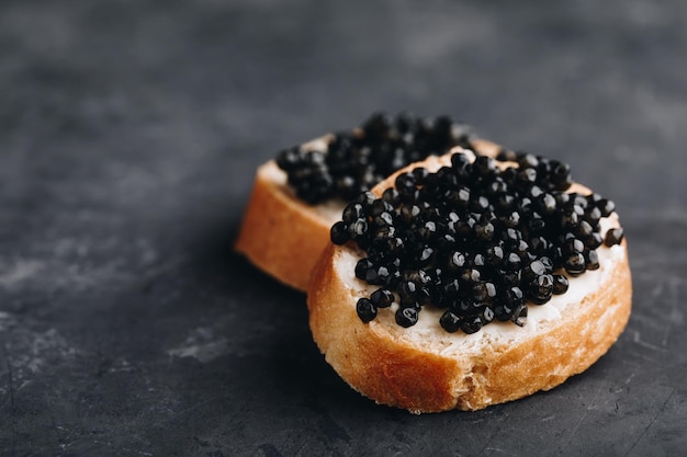 Panini al caviale nero con burro su fondo di cemento scuro