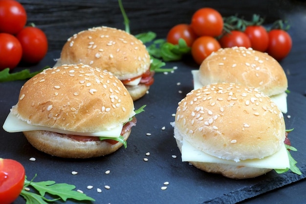 Panini al sesamo Hamburger di prosciutto e formaggio su uno sfondo di pomodori freschi e verdure