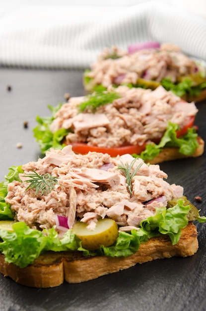 Panini al tonno con lattuga pomodori sottaceti e cipolle su ardesia