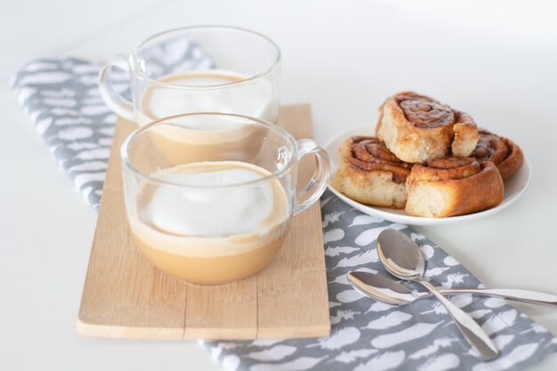 Panini alla cannella e tazza di caffè su sfondo bianco