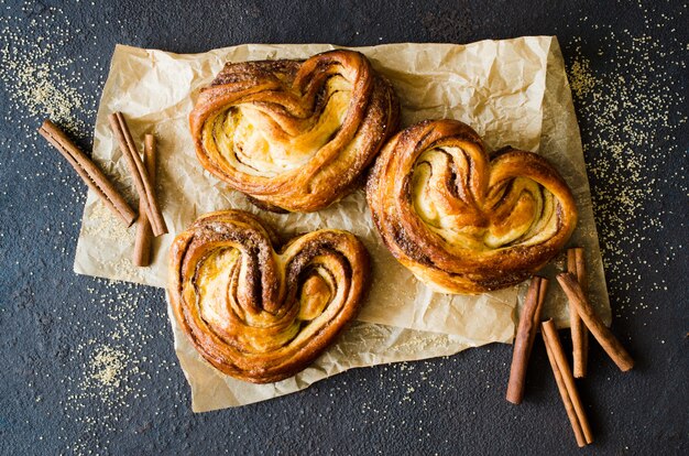 Panini alla cannella fragranti freschi al forno. Dolci tradizionali fatti in casa su sfondo scuro.