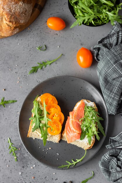 Panini aperti con pane di grano e segale, pomodori, salmone affumicato e rucola