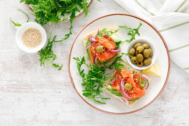 Panini aperti con salmone salato avocado olive e rucola Prima colazione Vista dall'alto