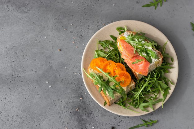 Panini aperti sani con pane artigianale con crema di formaggio, salmone, pomodori e rucola