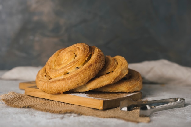 Panini appena sfornati di panini alla cannella sul tagliere con tong