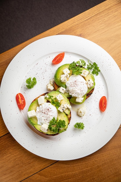 panini con avocado e uovo in camicia su un tavolo di legno in un ristorante