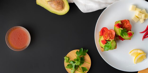 Panini con avocado fresco biologico e pomodoro rosso su superficie nera, colazione vegana