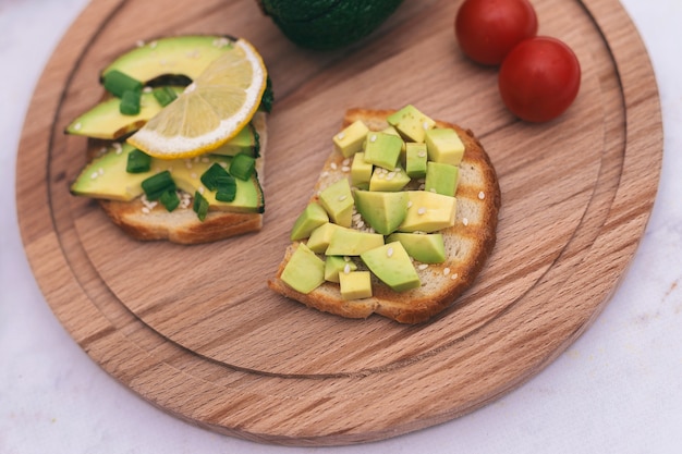 Panini con avocado, pomodori ed erbe aromatiche su uno sfondo di legno sul tavolo.