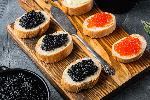 Panini con baguette al caviale rosso e nero, su fondo grigio