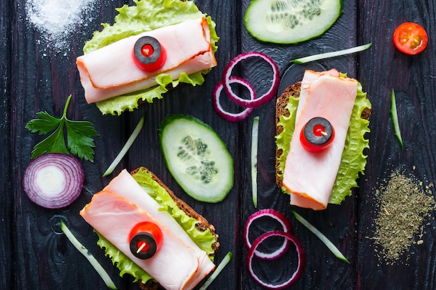 Panini con carne sulle foglie della lattuga con le verdure sul nero