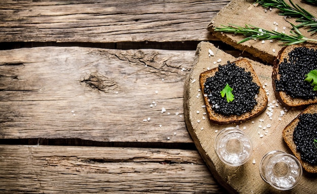 Panini con caviale nero e vodka. Su un tavolo di legno. Spazio libero per il testo. Vista dall'alto