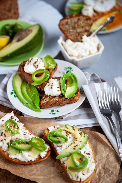 Panini con formaggio morbido avocado e cetriolo La colazione è in tavola Cibo sano Pane tostato e spalmato Sandwich di avocado stilllife Cibo sano Pane tostato