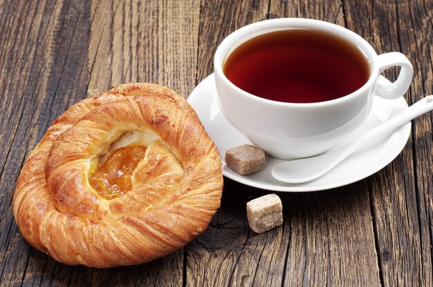 Panini con marmellata e tazza di tè sul tavolo di legno