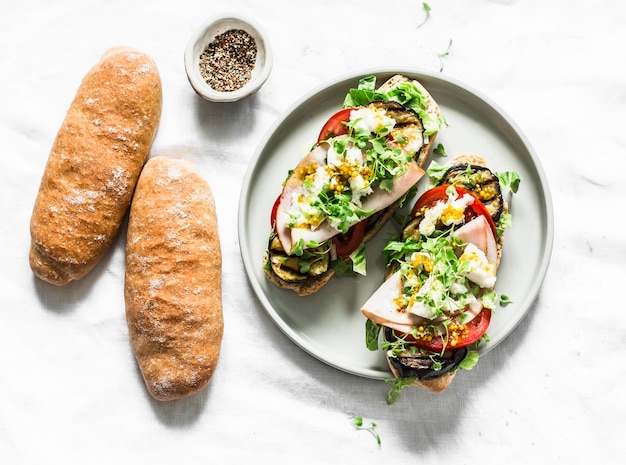 Panini con melanzane grigliate, pomodoro, prosciutto, mozzarella e micro verdi