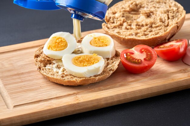 Panini con pomodori uova e maionese su un piatto di legno