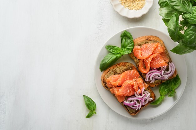 Panini con salmone salato avocado guacamole cipolle rosse e basilico Smorrebrod Set di panini aperti danesi Colazione salutare Cibo pulito Dieta concetto di cibo vegano Vista dall'alto