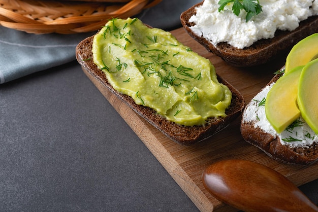 Panini con una cagliata tritata di avocado ed erbe aromatiche sul tagliere di legno naturale