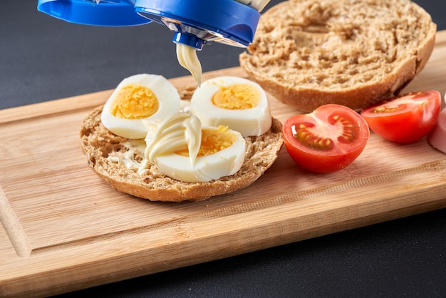 Panini con uova di pomodoro e maionese su un piatto di legno