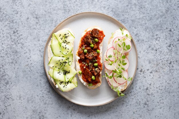 Panini con verdure, ravanelli, pomodori, cetrioli e microgreens su grigio. vista dall'alto