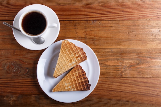 Panini della cialda con latte condensato bollito in piatto sulla tavola di legno marrone con la tazza di caffè. vista dall&#39;alto