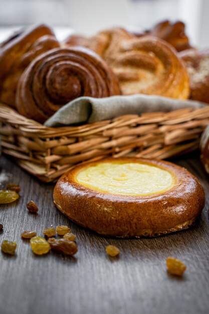 Panini di pasticceria fresca nel cestino in panetteria in stile rustico con grano bianco sulla tavola di legno