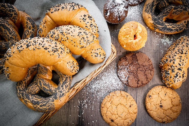 Panini di pasticceria fresca nel cestino in panetteria in stile rustico con grano bianco sulla tavola di legno