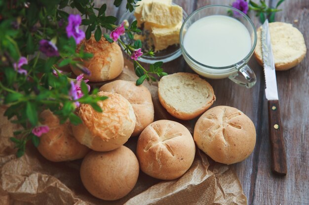 Panini e bicchiere di latte di segale casalinghi di recente al forno sulla tavola di legno nello stile rustico