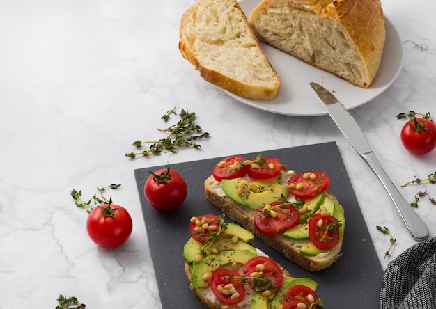 Panini fatti in casa con crema di formaggio avocado, pomodori e timo con olio d'oliva