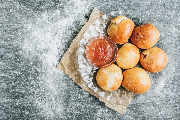 Panini freschi di lievito al forno ripieni di marmellata di mele su sfondo grigio con farina.