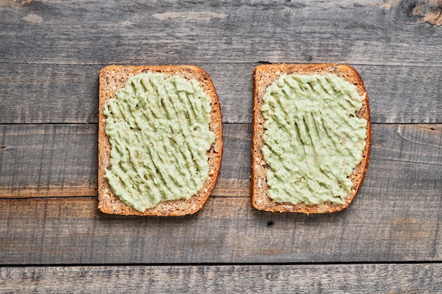 Panini integrali con guacamole. Prima colazione su un vecchio tavolo di legno.