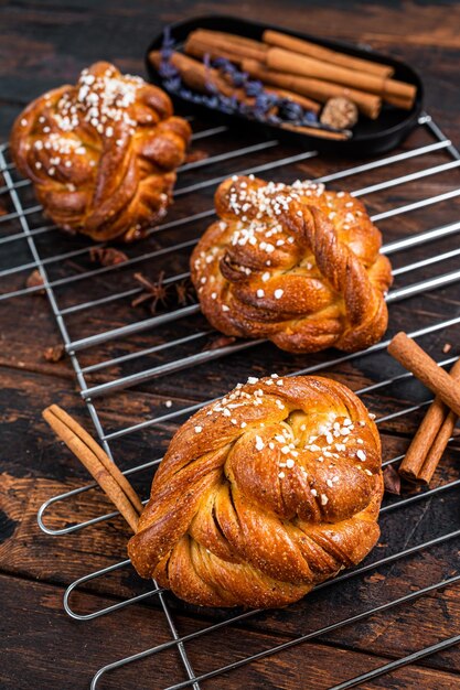 Panini o panini alla cannella appena sfornati fatti in casa, Kanelbullar svedese. Fondo in legno scuro. Vista dall'alto.