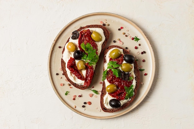 Panini per la colazione con pomodori secchi, olive e crema di formaggio vista dall'alto