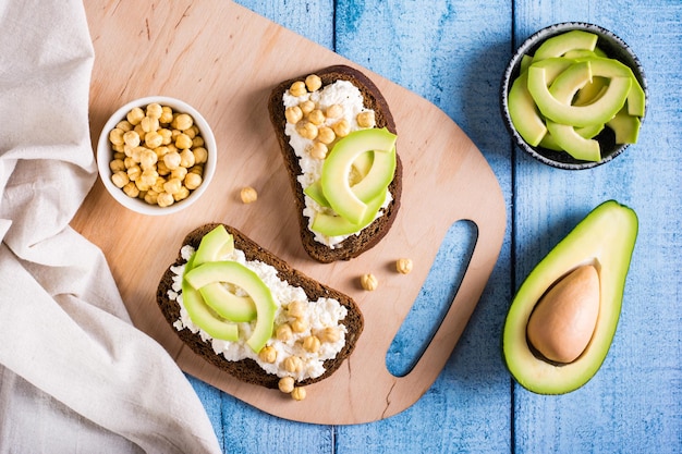 Panini su pane di segale con ricotta avocado e ceci su una tavola Cibo sano Vista dall'alto