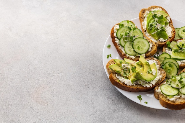 Panini verdi vegetariani con avocado e cetriolo con microgreens su sfondo chiaro