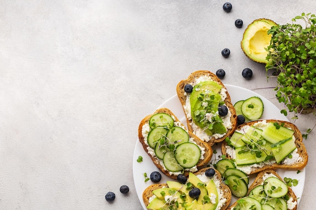 Panini verdi vegetariani con avocado e cetriolo con microgreens su sfondo chiaro